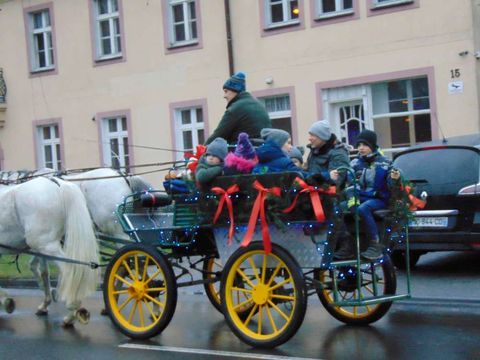 Grupa mieszkańców jadąca bryczką, ciągniętą przez dwa konie, ulicą Rynkową w Budzyniu